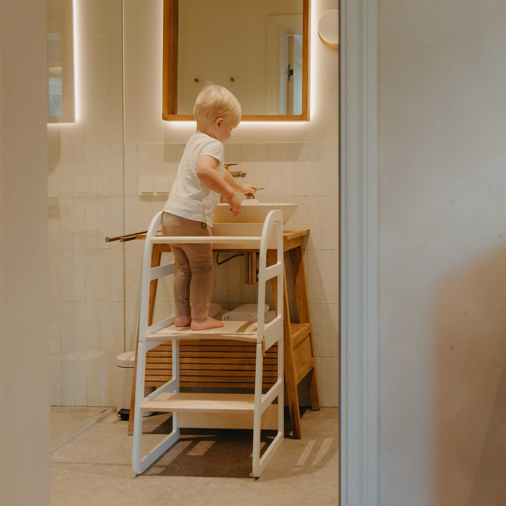 7. Child using white kitchen tower at bathroom sink