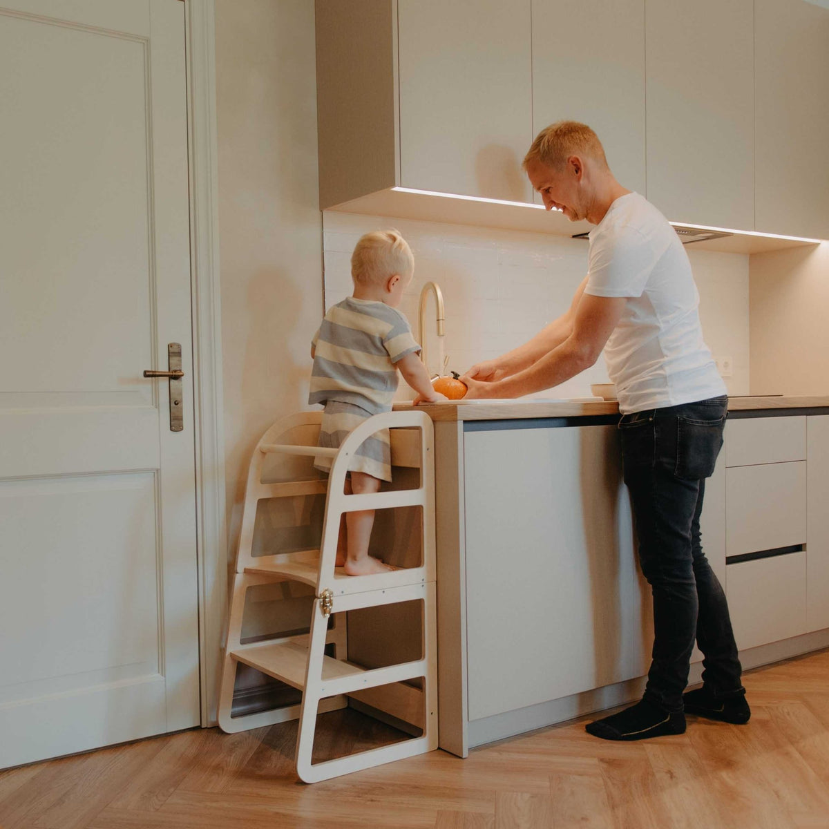11. Child and adult using white kitchen tower at kitchen counter