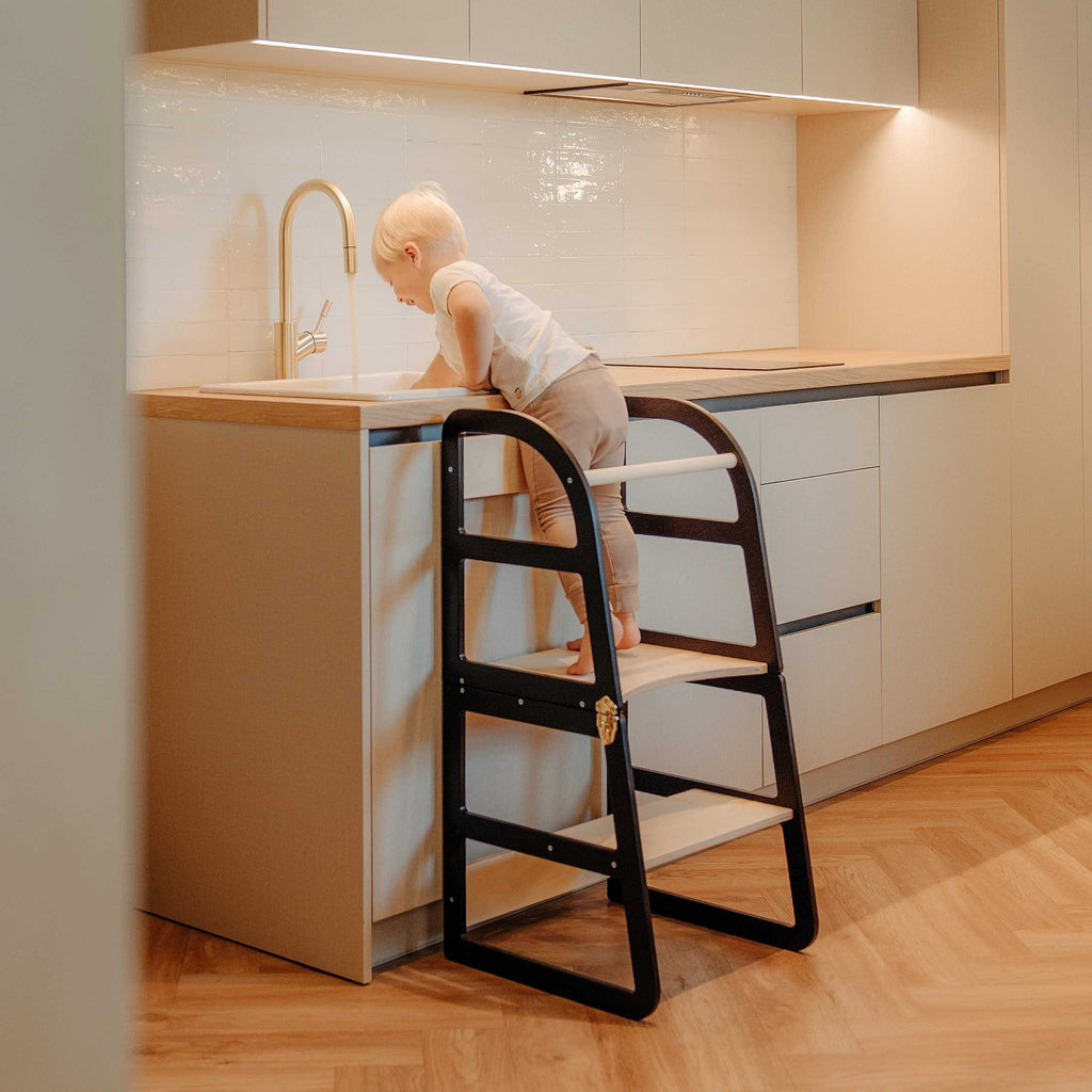 19. Child using black kitchen tower at kitchen sink in modern home
