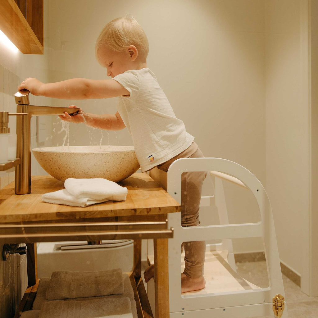 8. Close-up of child using white kitchen tower at bathroom sink