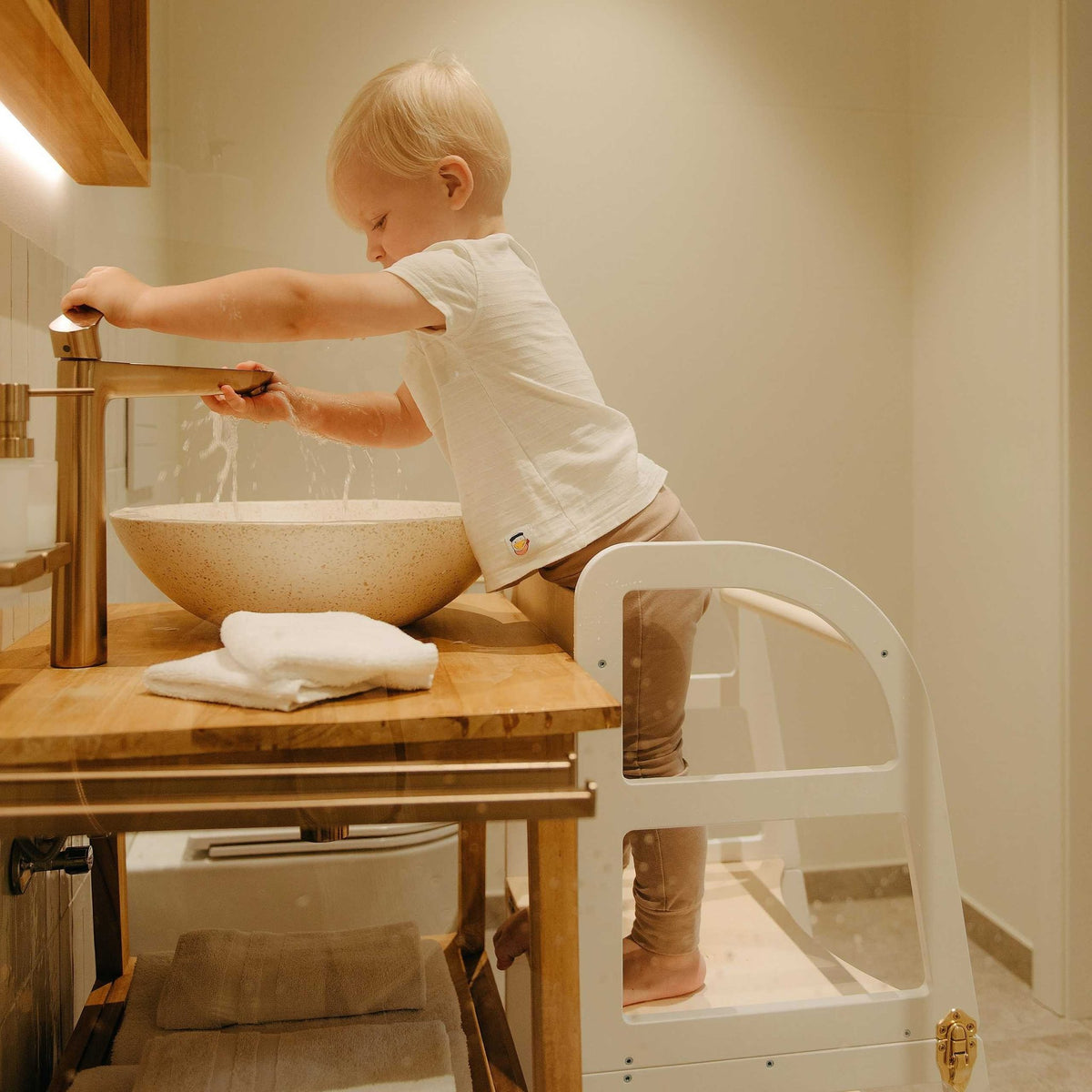 8. Close-up of child using white kitchen tower at bathroom sink