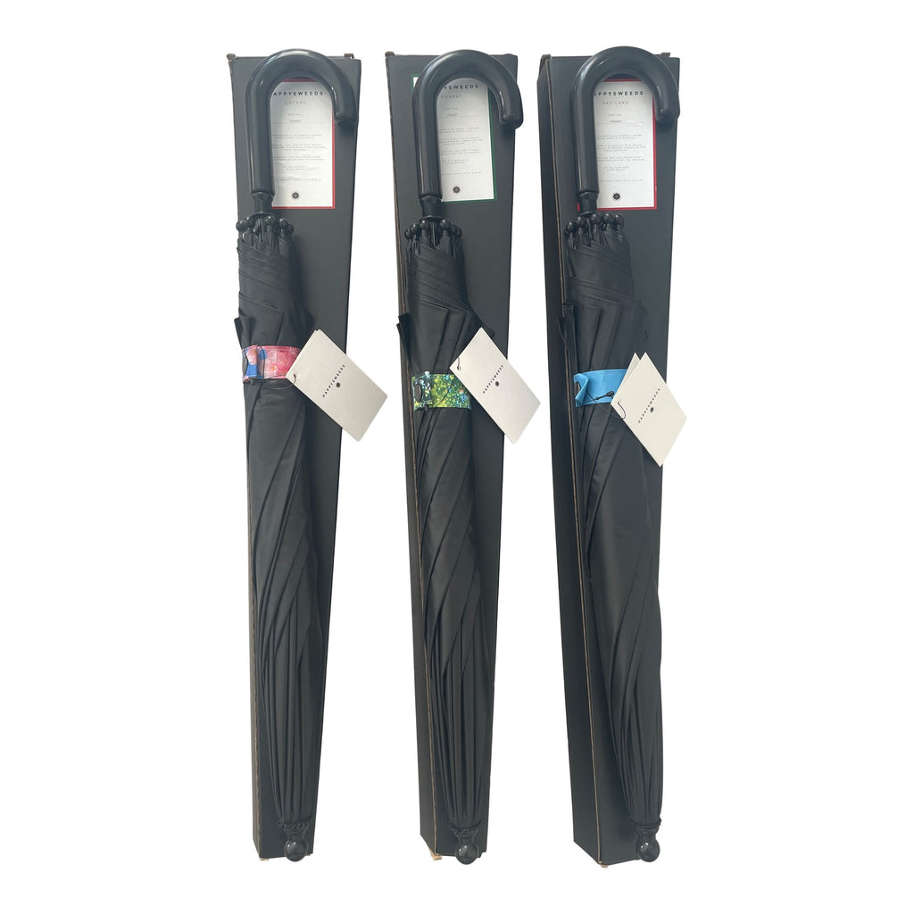 2. Three packaged children's umbrellas with black covers and colorful forest-themed bands, featuring curved handles and tags, displayed upright