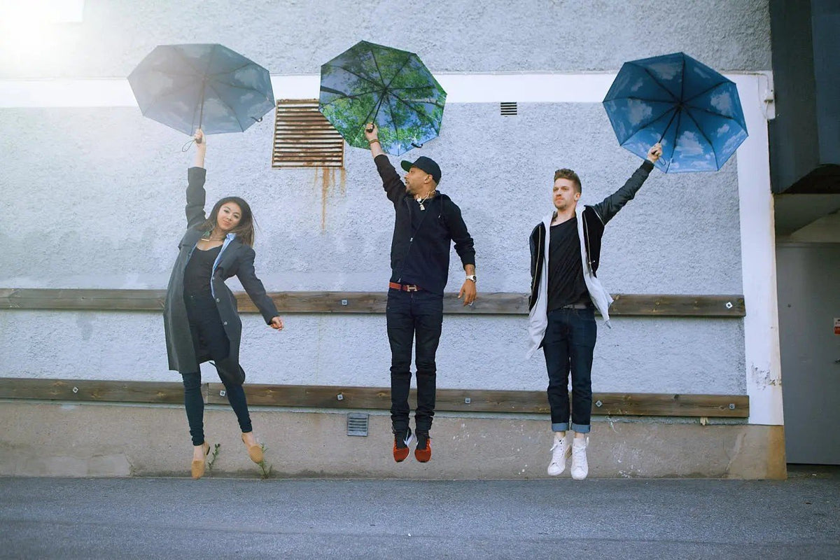 1. Three people holding forest print umbrellas jumping in urban setting