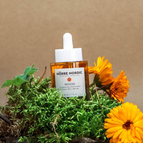 2. Nörre Nordic REVIVE Brightening Antioxidant Face Oil Serum bottle on natural setting with flowers