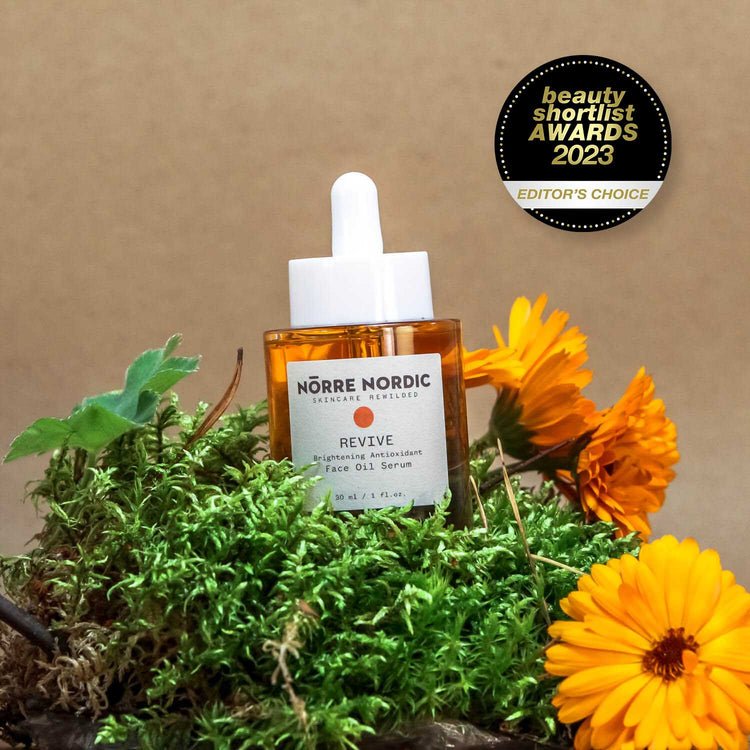 3. Nörre Nordic REVIVE Brightening Antioxidant Face Oil Serum with award badge, surrounded by greenery and flowers