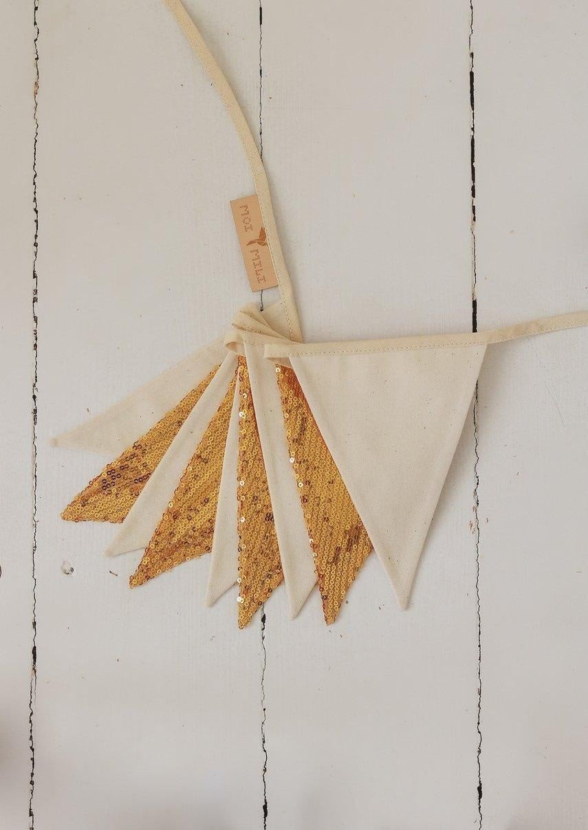 2. Studio shot of gold and beige sequin garland with moi mili tag on white wooden background