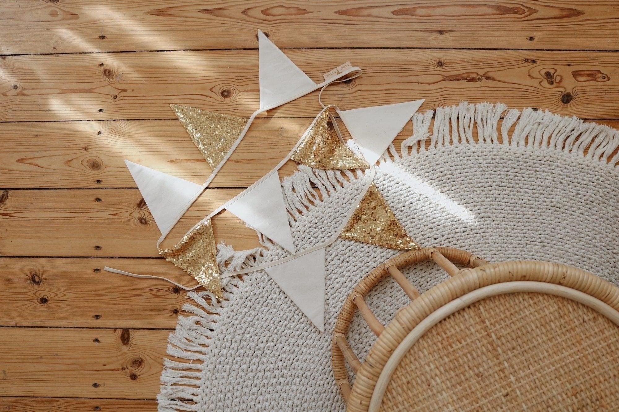 4. Flat lay of gold and beige sequin garland on wooden floor with woven rug