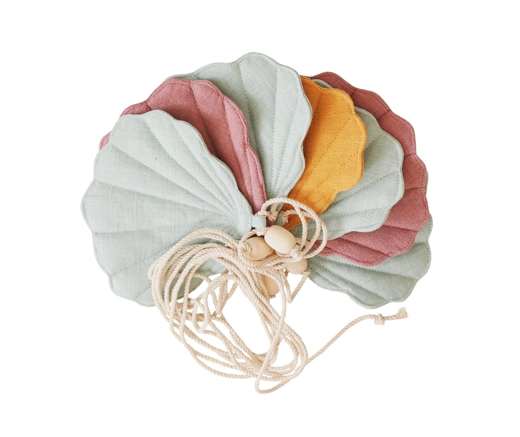 2. Studio shot of moi mili Shell Garland featuring mint, dirty pink, and mango linen shells on a cotton string with wooden beads