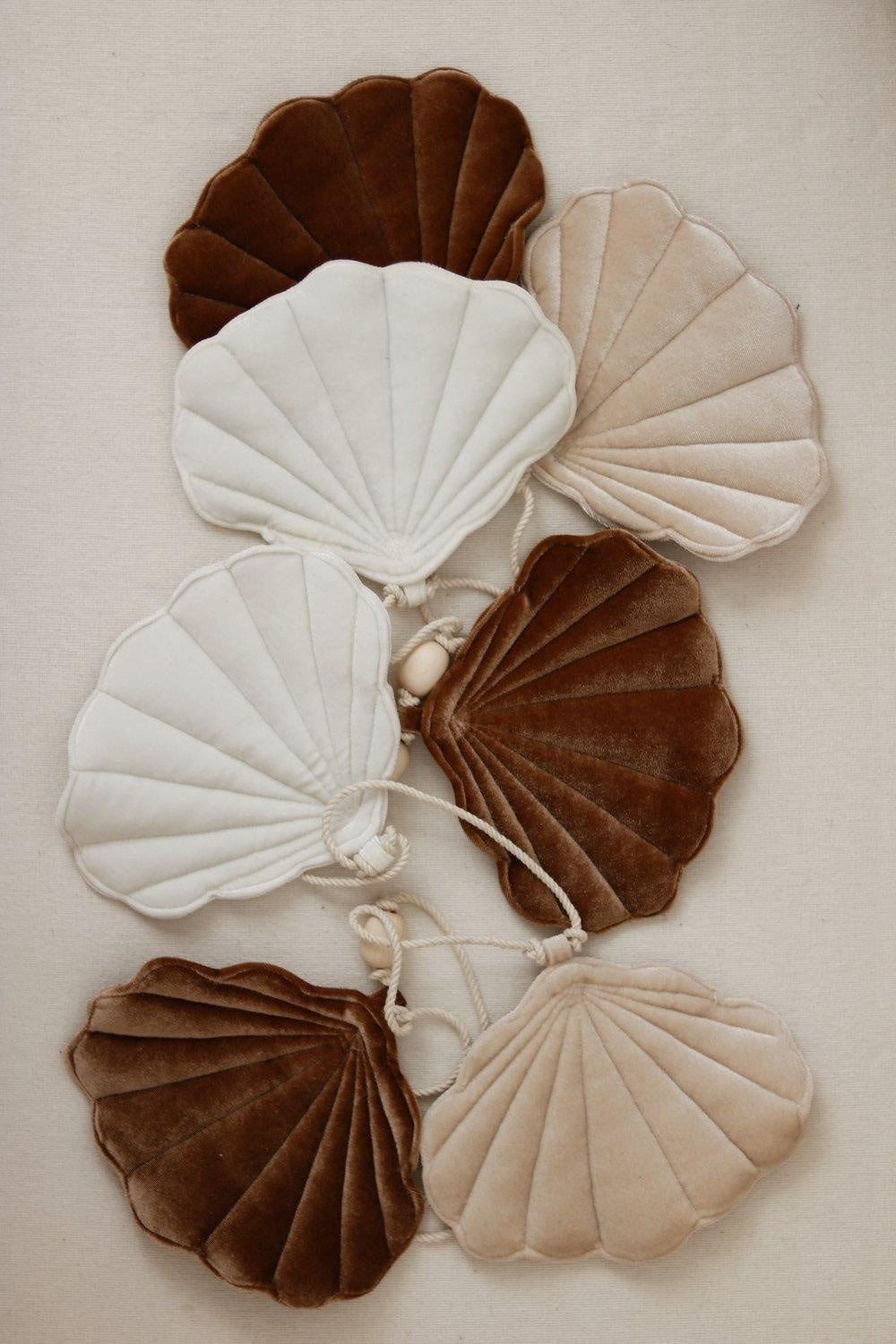 5. Flat lay of velvet shell garland in brown, beige, and cream colors with wooden beads on a neutral background