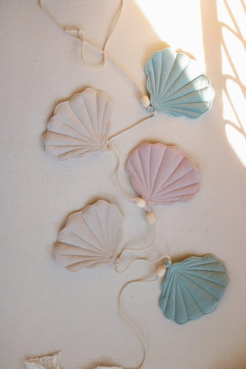 3. Close-up of pastel velvet shell pendants on a cotton string with wooden beads, laid on a light surface