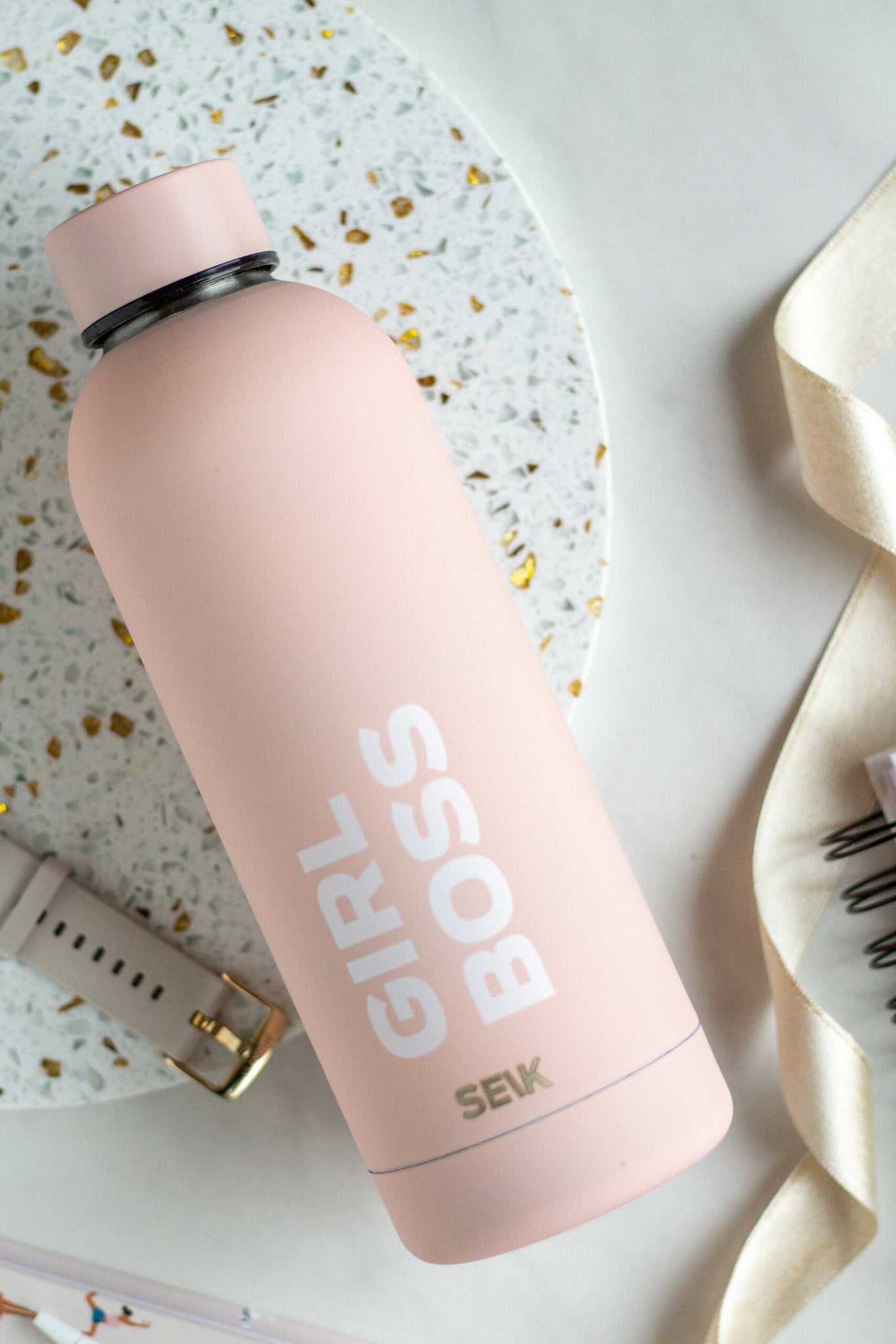 1. SEIK Girl Boss water bottle in pink, shown on a stylish desk setting with accessories