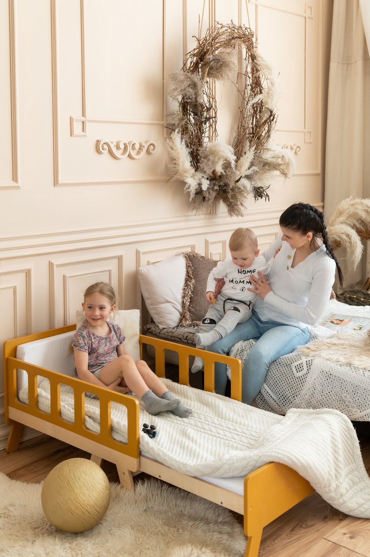 21. Woman with two children on yellow growing bed and large bed in cozy room