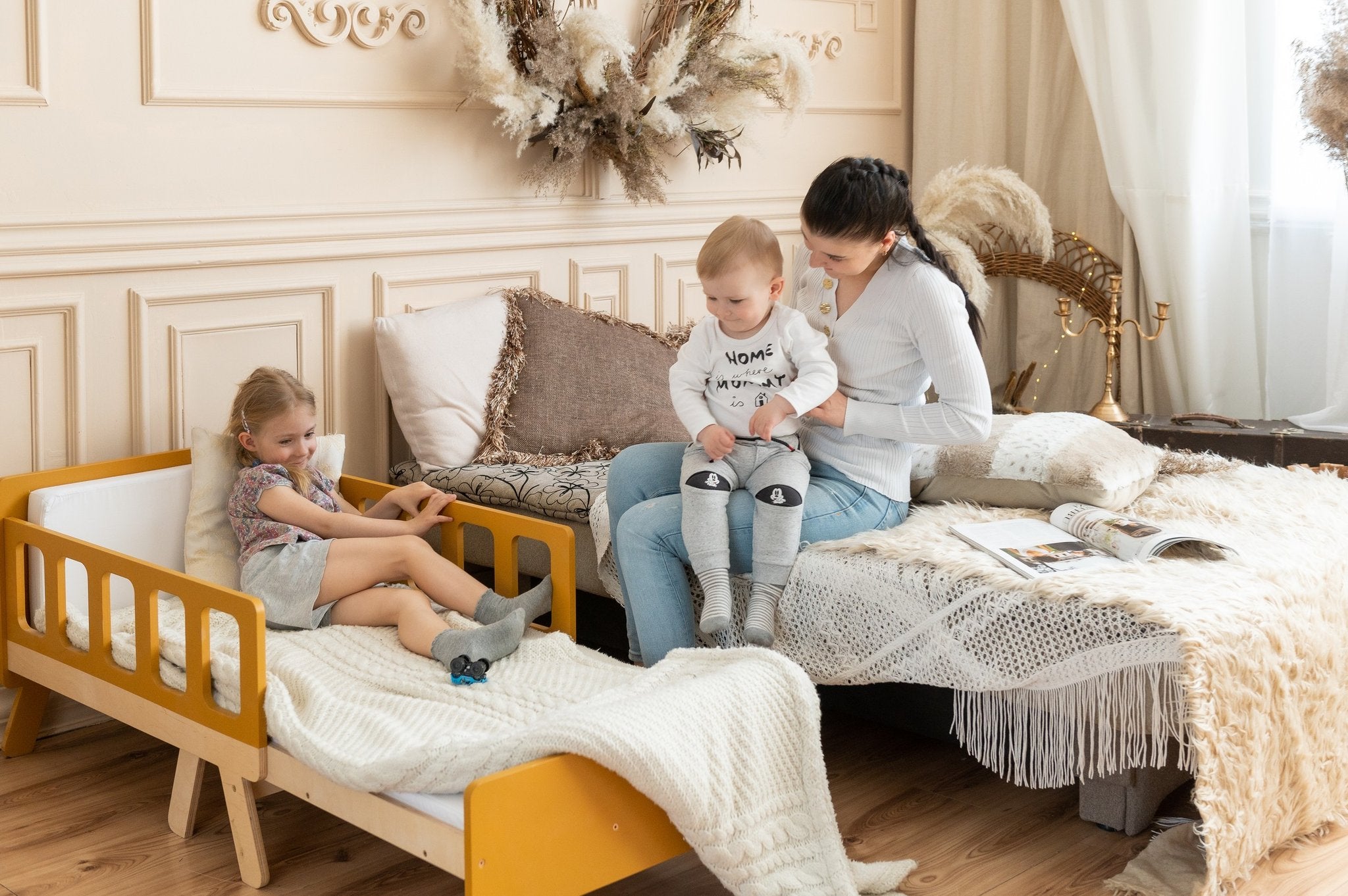 24. Woman with two children on yellow growing bed and large bed in cozy room