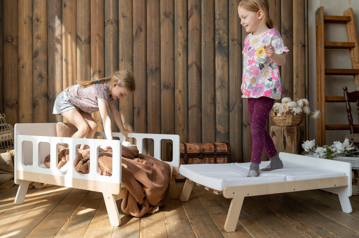 20. Two children playing on white growing bed with brown blanket in wooden room