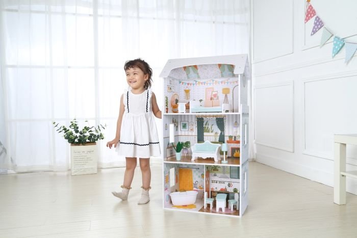 1. Young girl in white dress standing next to Gerardo's Toys wooden dollhouse Luna with LED lights in a bright room
