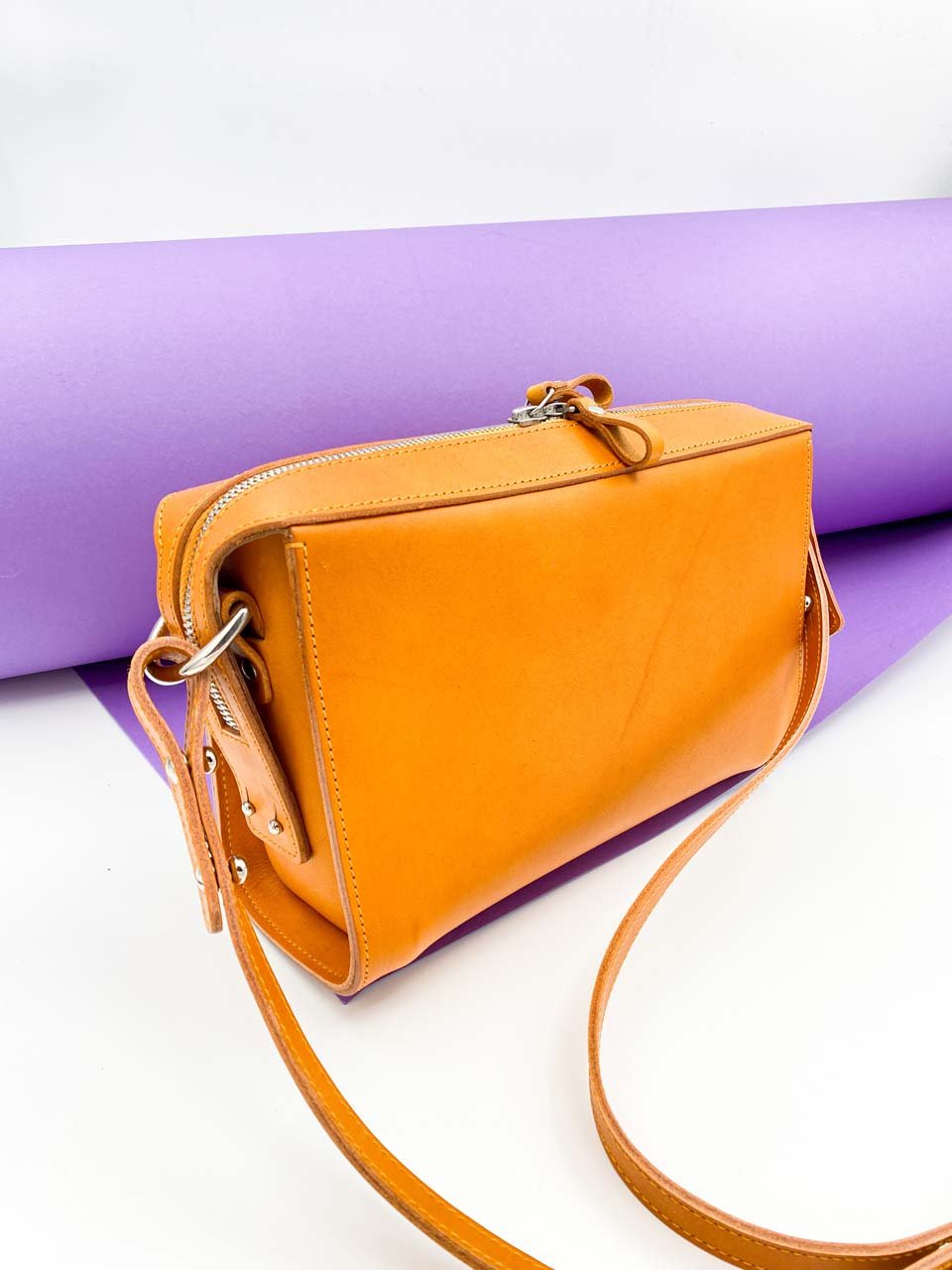 6. Orange Stella Soomlais Treasure Box handbag with adjustable strap on white and purple background