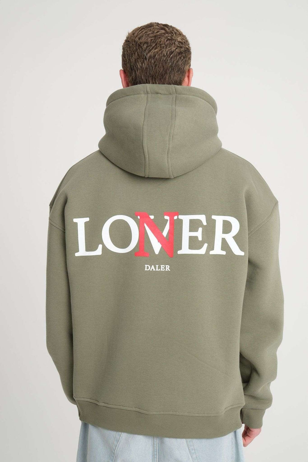2. Back view of men's olive green hoodie with 'LONER' and 'DALER' print, worn by model in studio setting