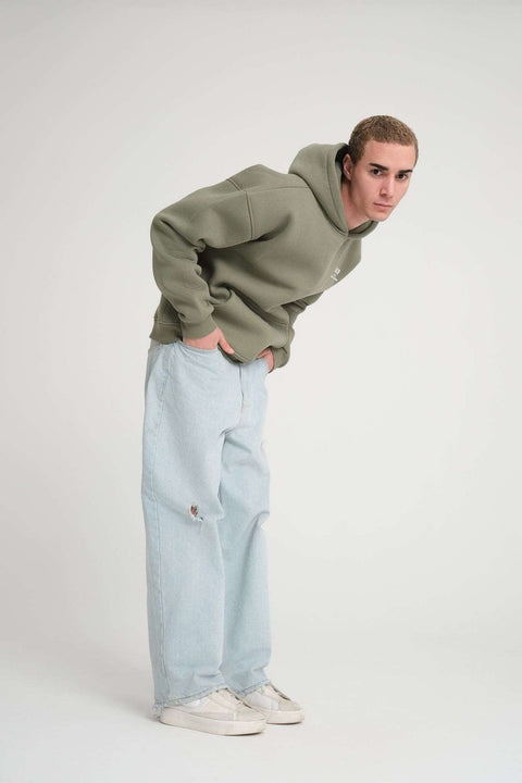 1. Full body view of man wearing olive green hoodie and light jeans, posing in studio