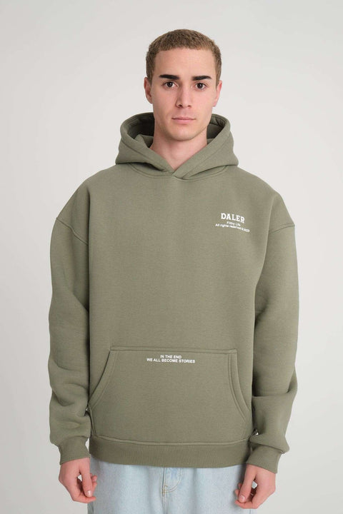 1. Front view of man wearing olive green hoodie with 'DALER' logo and pocket text, in studio setting