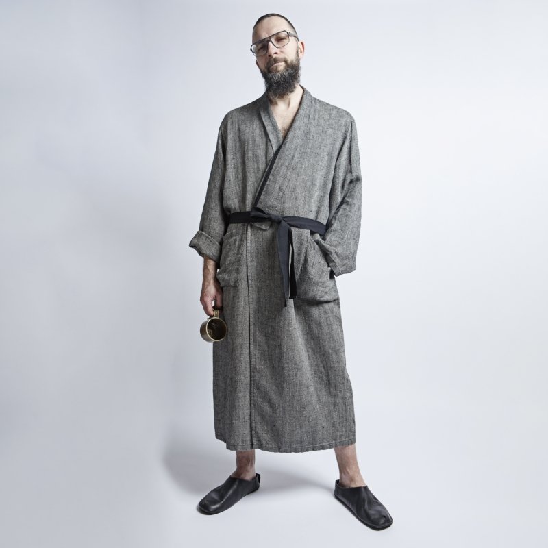 3. Man in grayish-black linen bathrobe with fishtail pattern and black belt, holding a mug, in studio setting