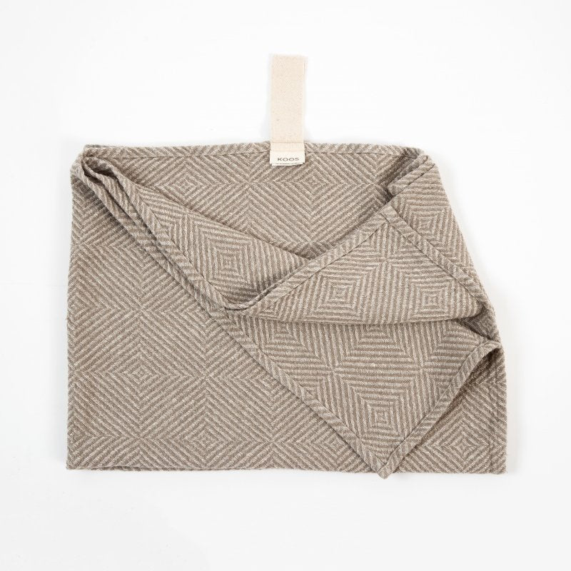 4. Beige linen towel with checkered fishbone pattern, partially unfolded, showing KOOSdisain label and white cotton hanger