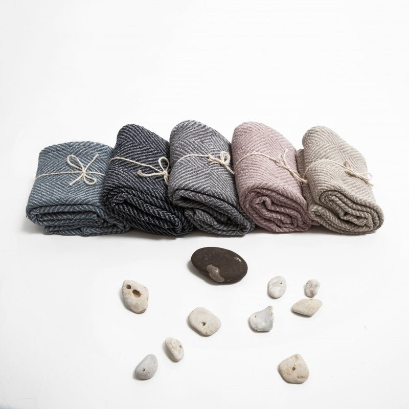 3. Rolled linen towels in various colors including beige, blue, and pink, tied with string, surrounded by small stones on white background