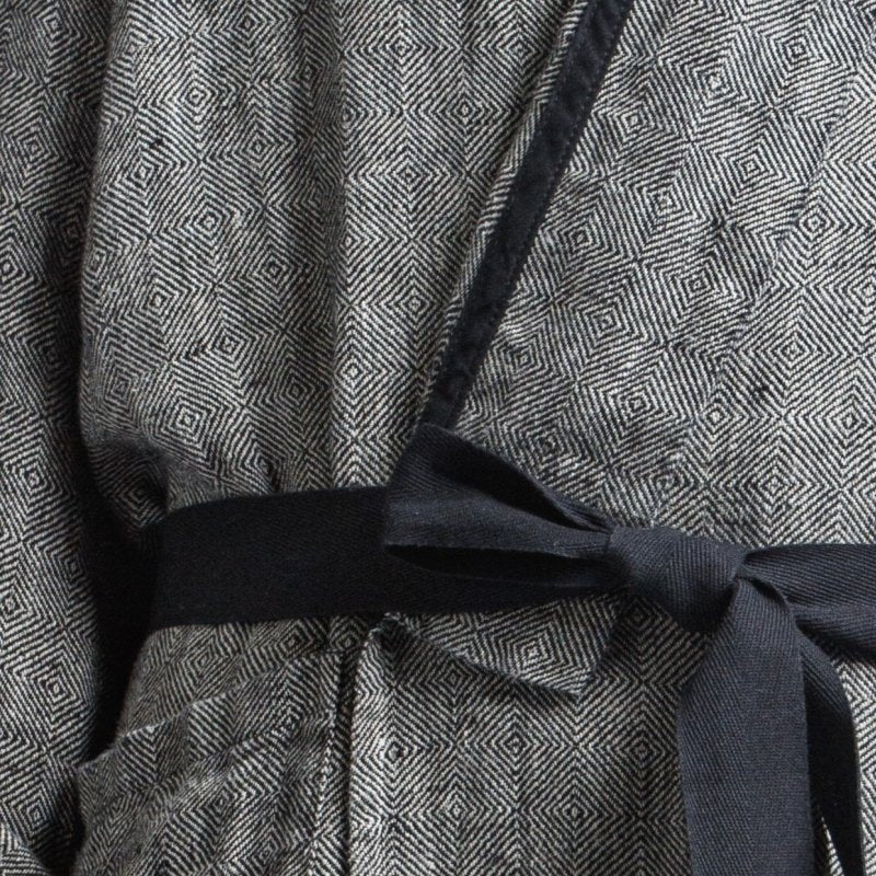 8. Close-up of black belt tied on grayish-black linen bathrobe with fishtail pattern, showing fabric detail