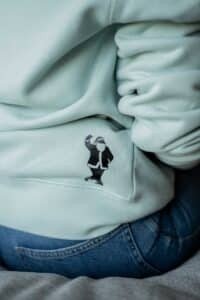 3. Close-up of light blue sweatshirt showing small Santa graphic near the hem