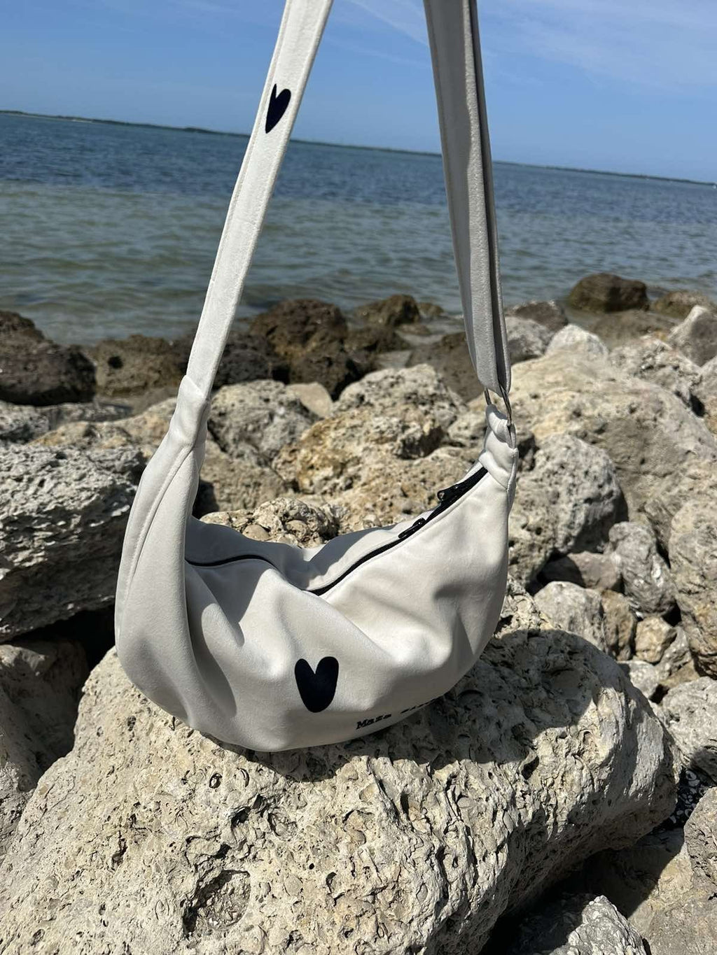 14. Garbanota Hobo Bag Heart in white on rocky beach, highlighting heart design and craftsmanship