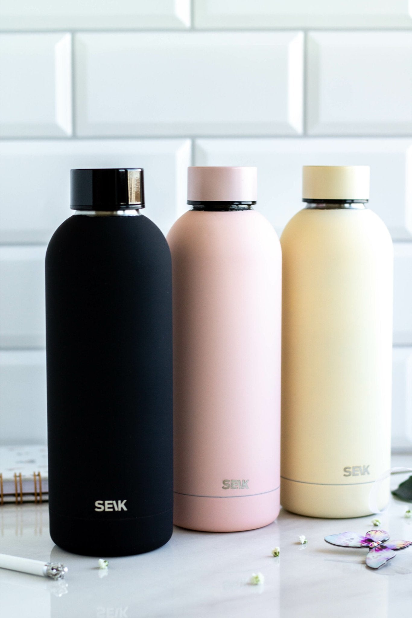 2. SEIK water bottles in black, pink, and cream colors displayed on marble surface