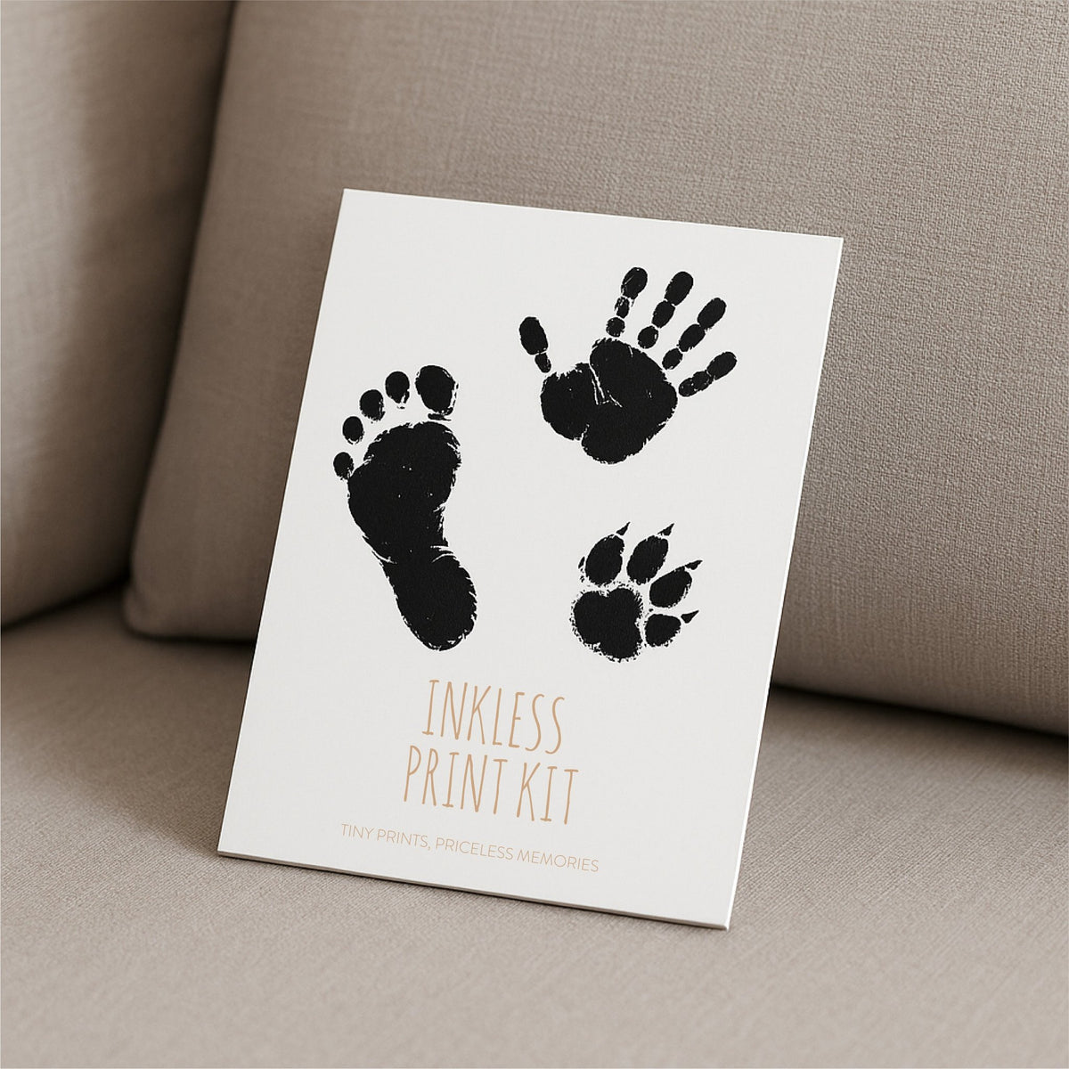 2. Beebila ink-free print kit packaging with black hand, foot, and paw prints on white paper, displayed on beige fabric