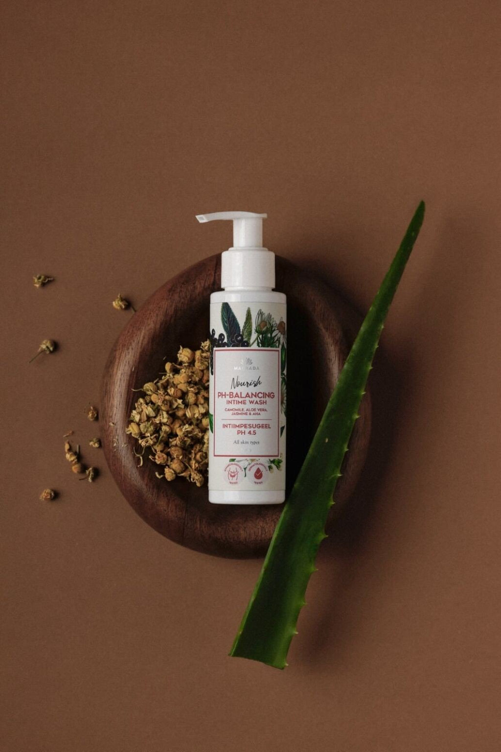 4. Flat lay of Magrada Organic Cosmetics intimate wash gel with chamomile and aloe, pH 4.5, on a wooden plate with chamomile flowers and aloe leaf