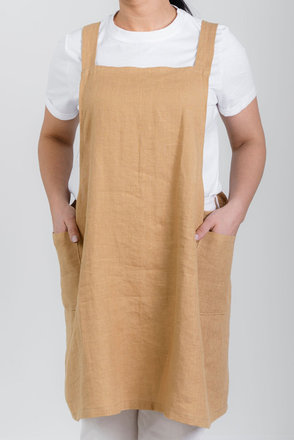 6. Front view of woman wearing beige Japanese-style linen apron with pockets over white shirt