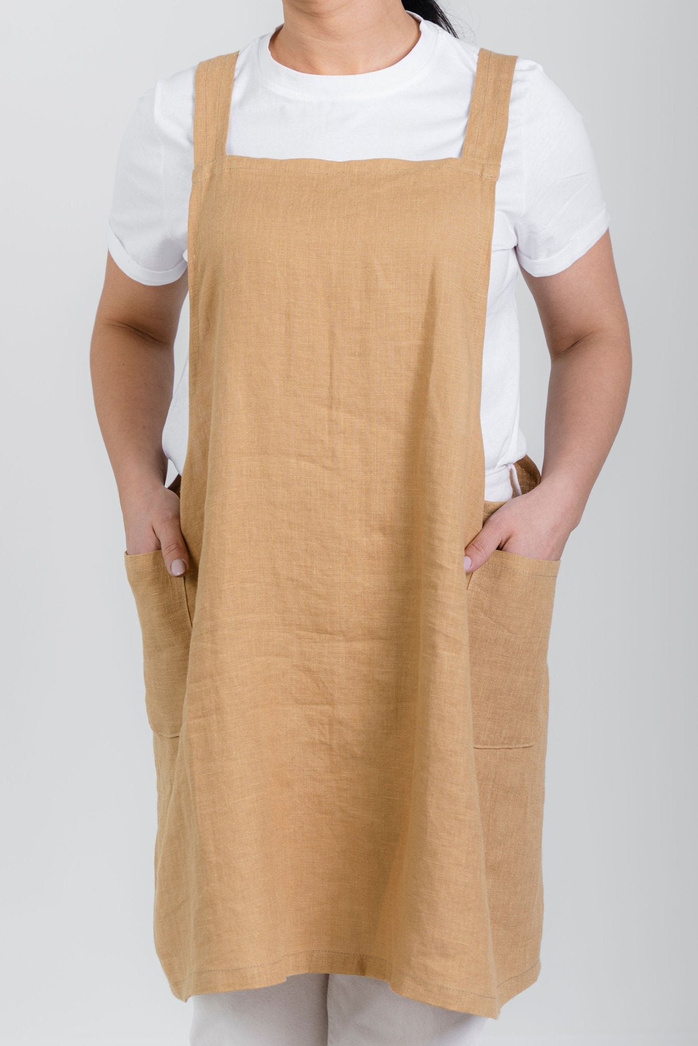 6. Front view of woman wearing beige Japanese-style linen apron with pockets over white shirt