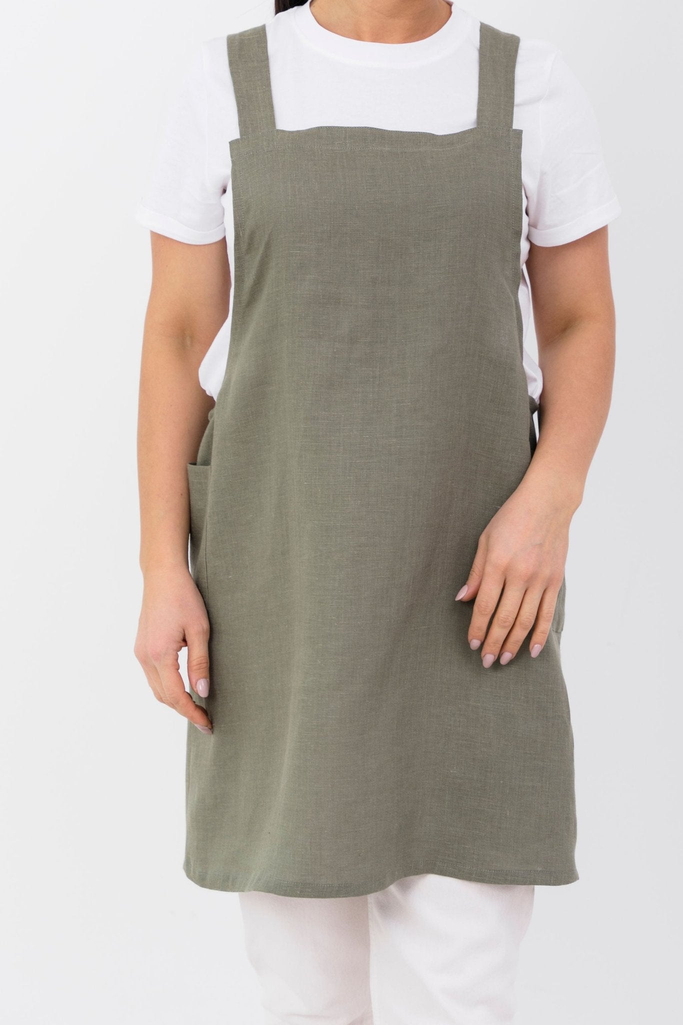 4. Front view of woman wearing olive green Japanese-style linen apron with pockets over white shirt