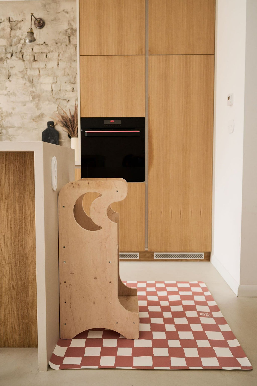 8. Pink and beige checkered floor mat under a wooden high chair in a modern kitchen