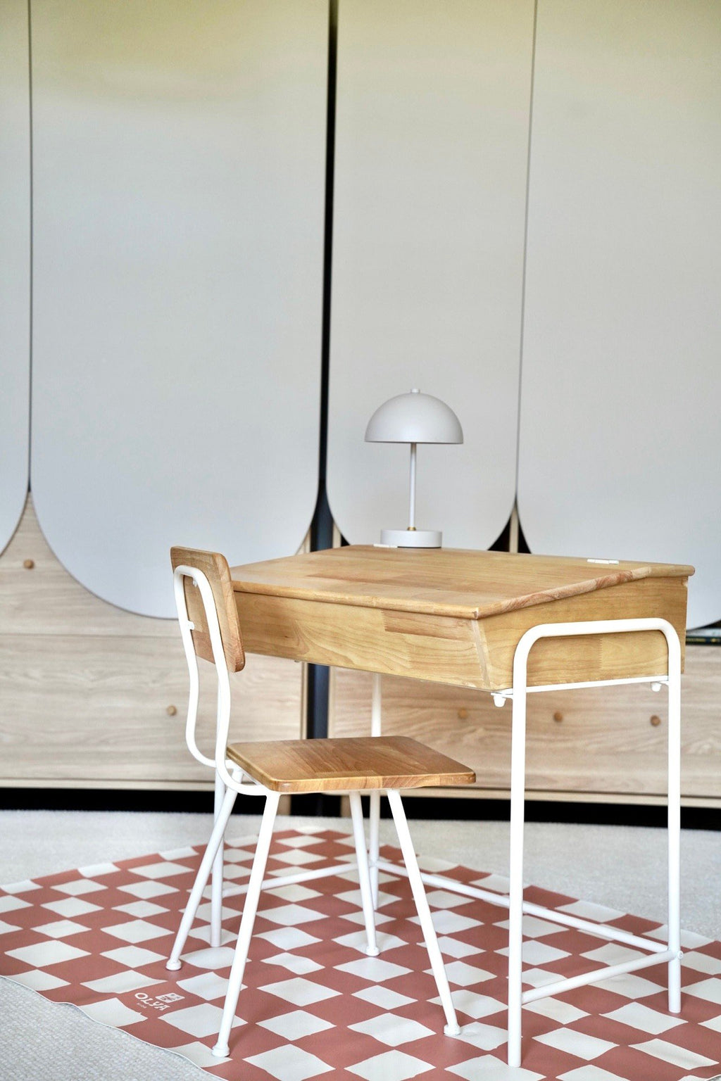 2. Pink and beige checkered floor mat under a wooden desk and chair in a minimalist room