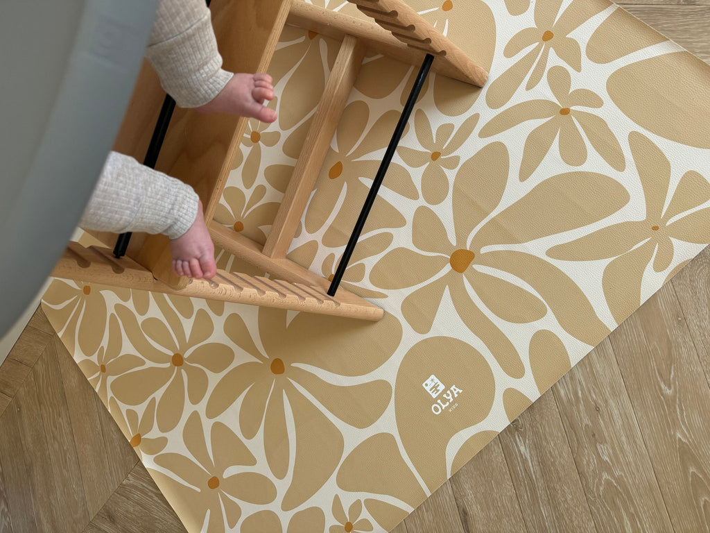 3. Close-up of beige daisy-patterned OLYA KIDS floor mat with toddler's feet