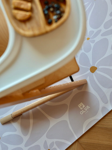 3. Close-up of OLYA KIDS logo on lavender daisy-patterned floor mat under high chair