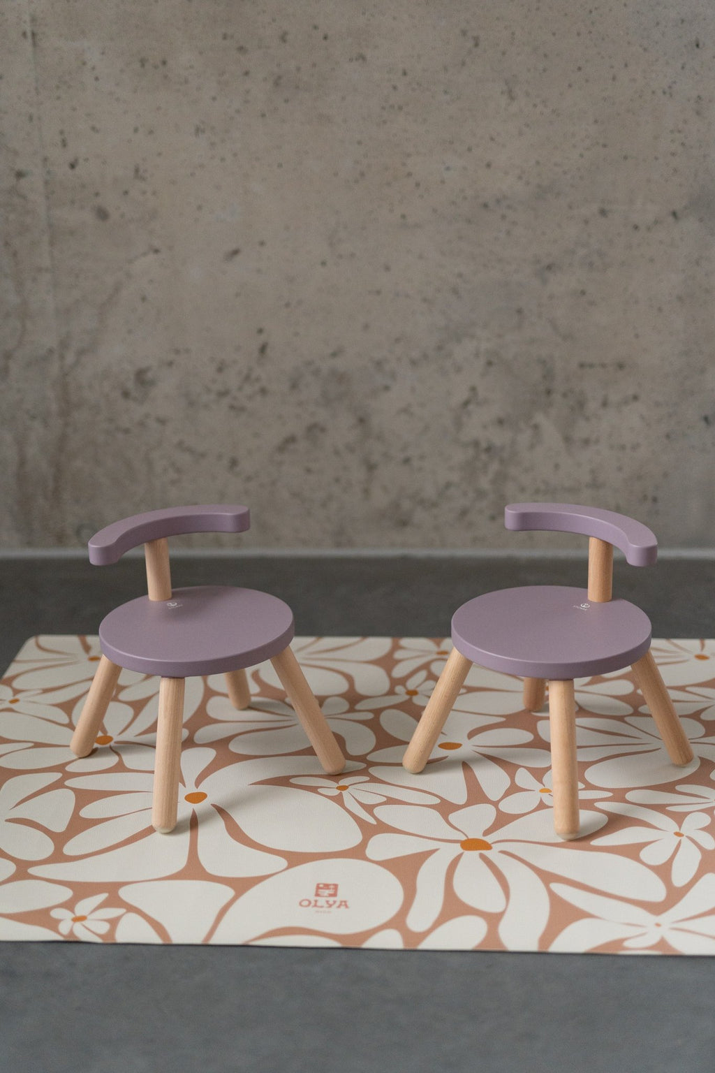 1. Two purple chairs on kids' daisy-patterned floor mat against concrete wall
