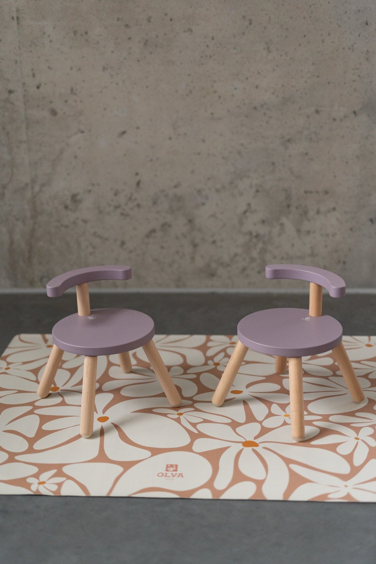 1. Two purple chairs on kids' daisy-patterned floor mat against concrete wall