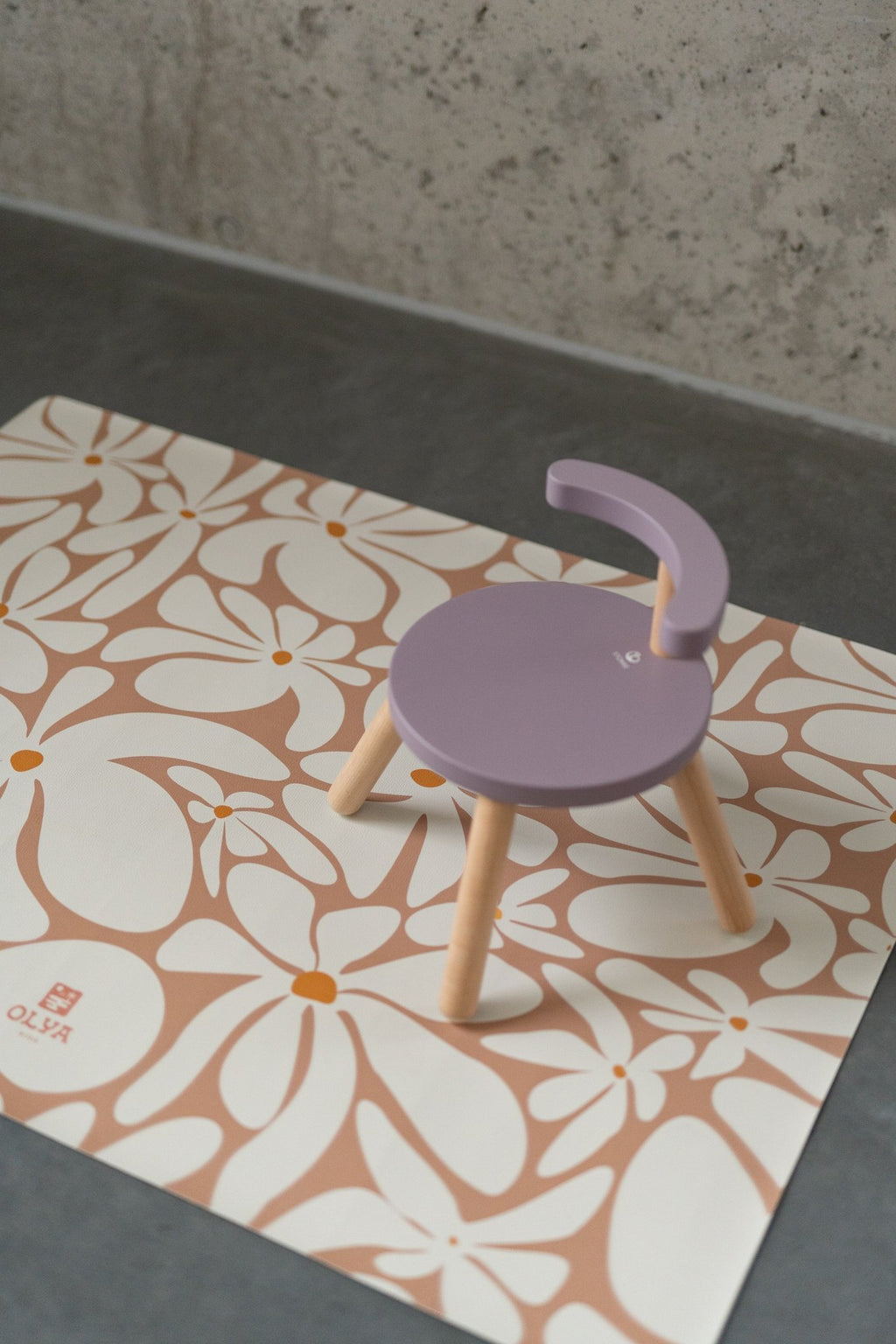 1. Kids' mealtime floor mat with daisy print and purple chair on concrete floor