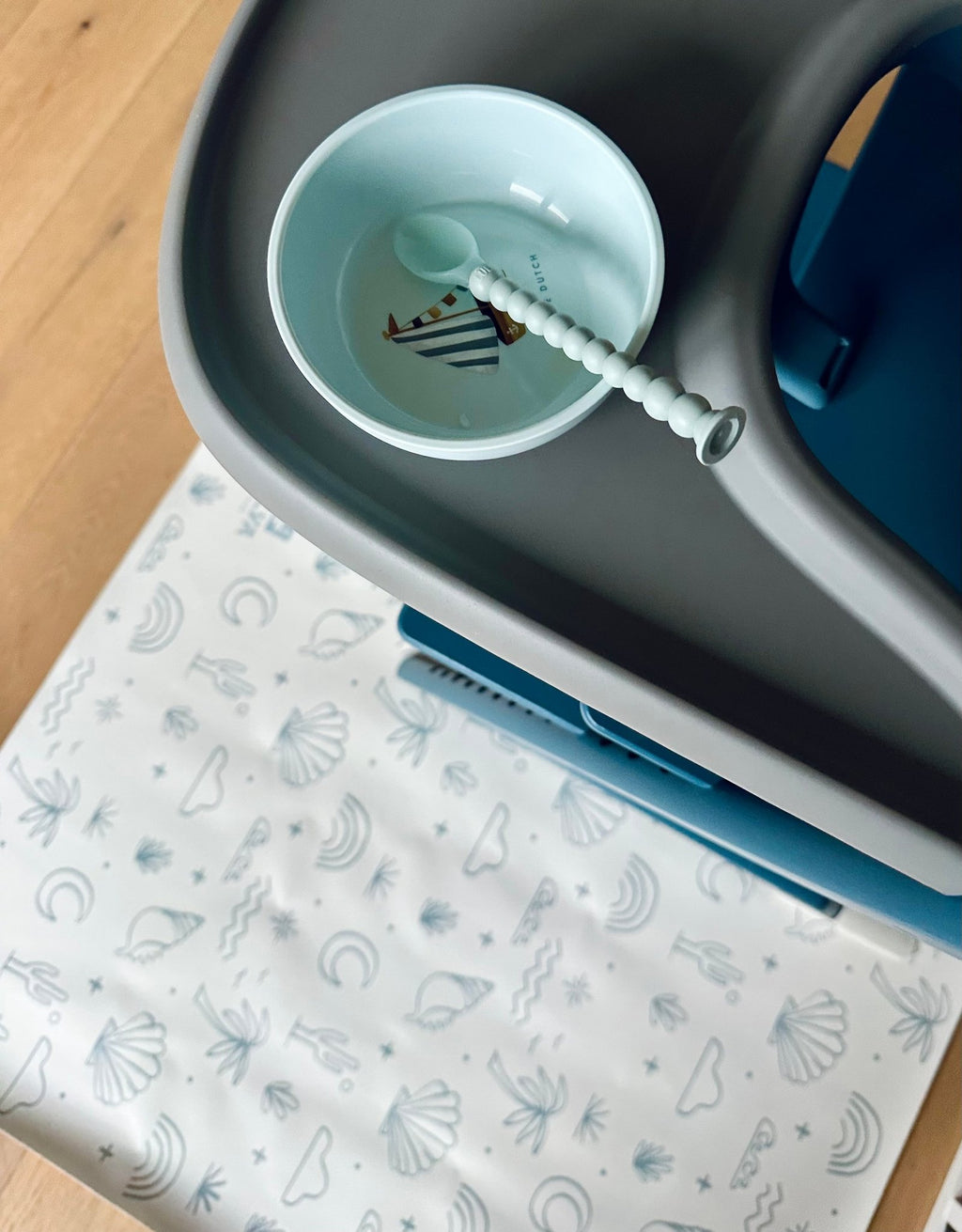 1. Baby in high chair with bowl on OLYA KIDS Palm Beach Azure floor mat