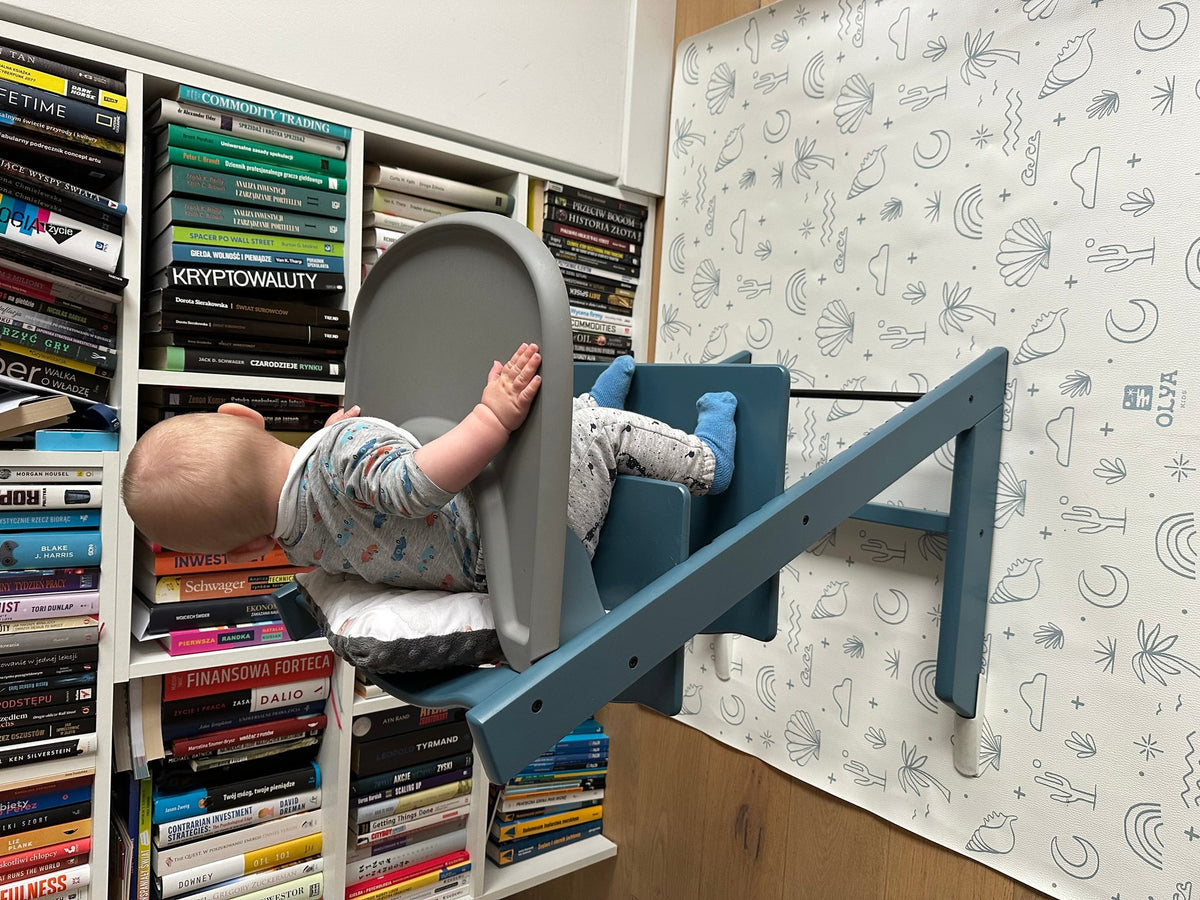 1. Baby in high chair on OLYA KIDS Palm Beach Azure floor mat with beach-themed patterns