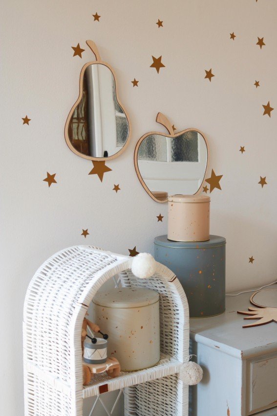 5. Pear and apple-shaped mirrors with plywood frames on wall with gold star decals above wicker and metal storage.