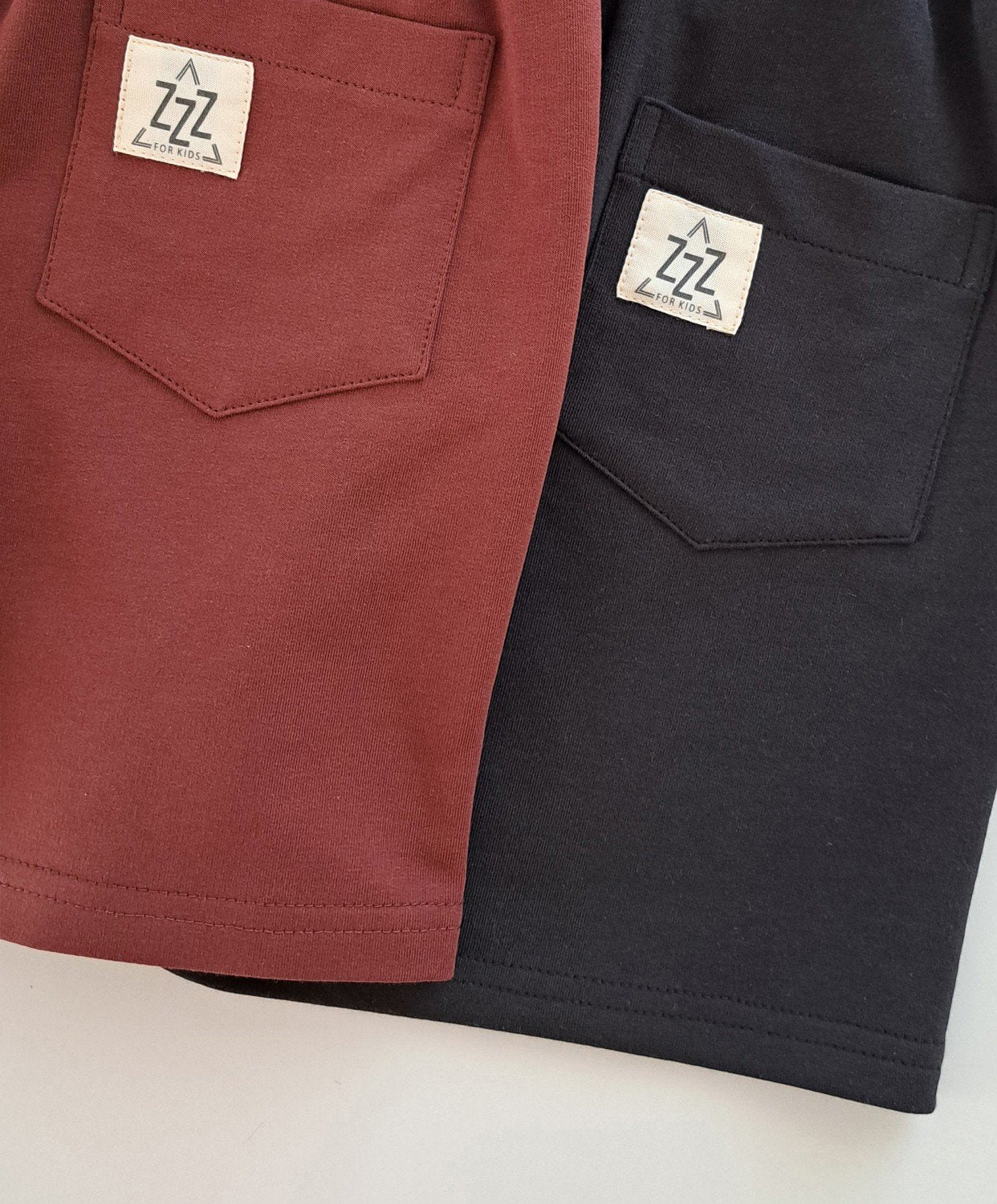 3. Detail of back pockets on rust and black kids shorts with Zezuzulla logo patch