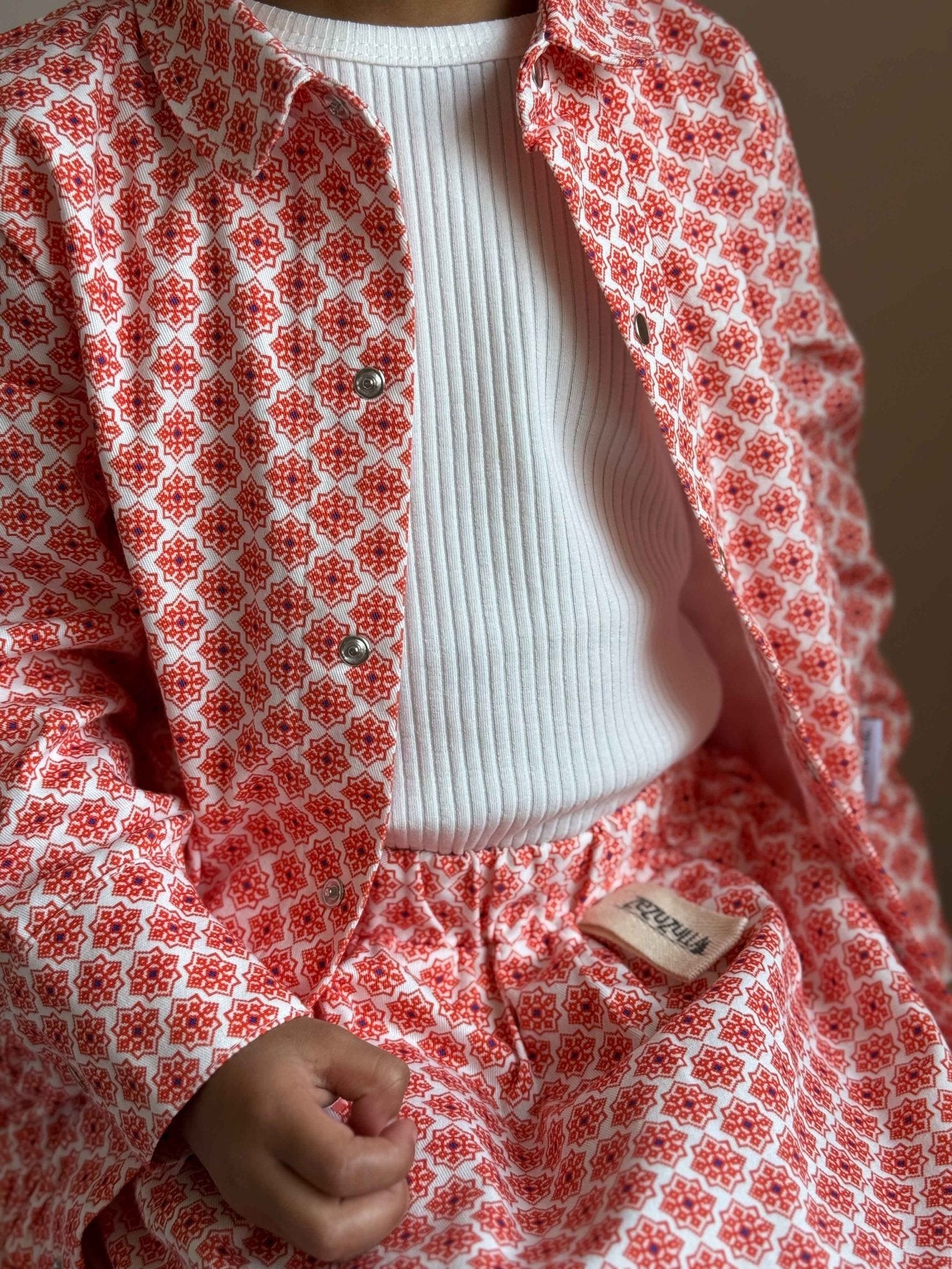 3. Close-up of Zezuzulla kids' skirt and jacket in red and white print with ribbed white shirt