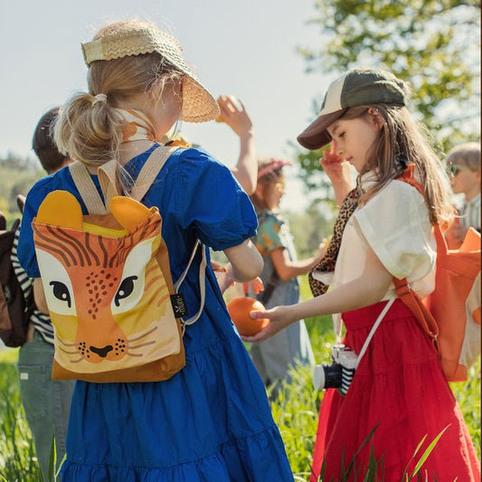 2. Two girls with Muni lion backpacks in a field, one in blue dress