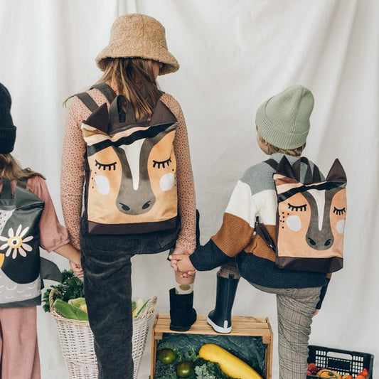 1. Kids wearing Muni horse backpacks in lifestyle setting, showcasing playful design