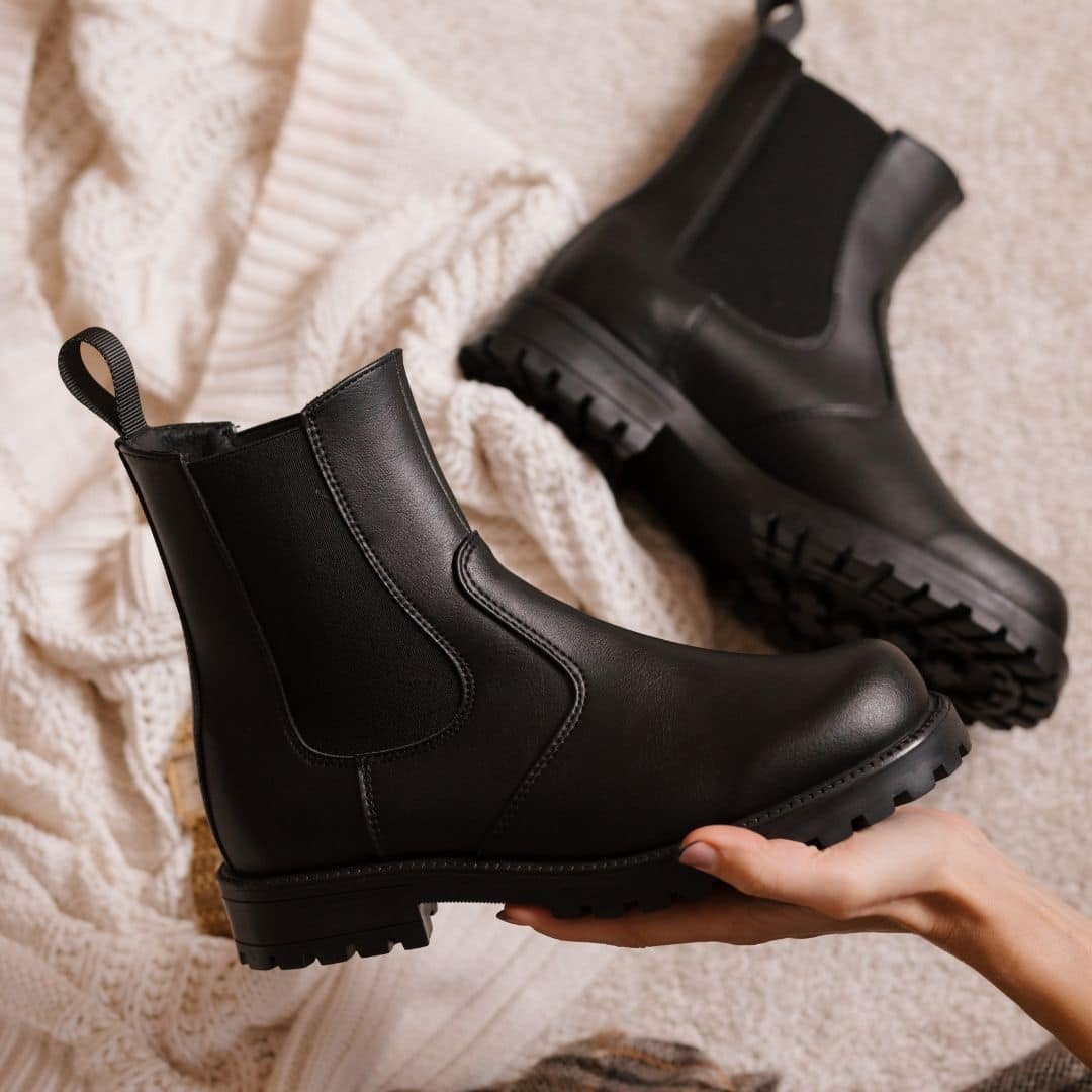 5. Close-up of KIRA 3.0 Chelsea Boots in black, held in hand, showing texture and detail